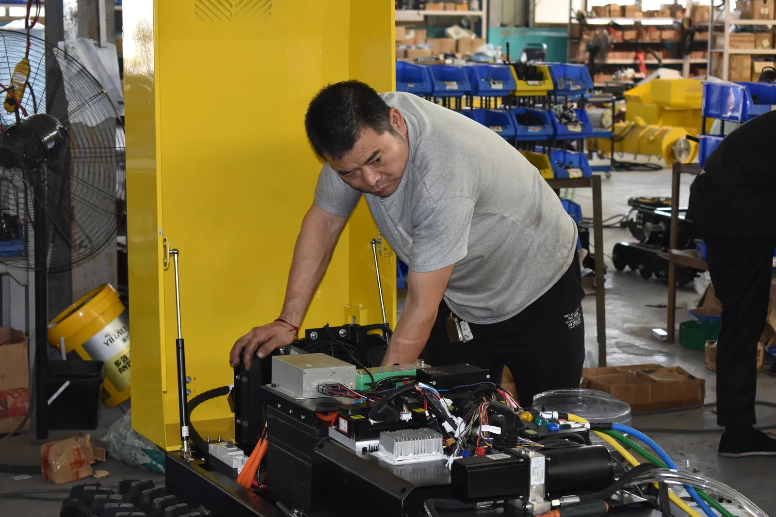 Technician working on the components beneath an open mower cover.