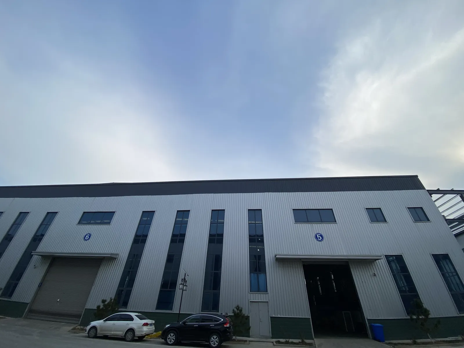 Front of an industrial workshop building with vehicles outside.