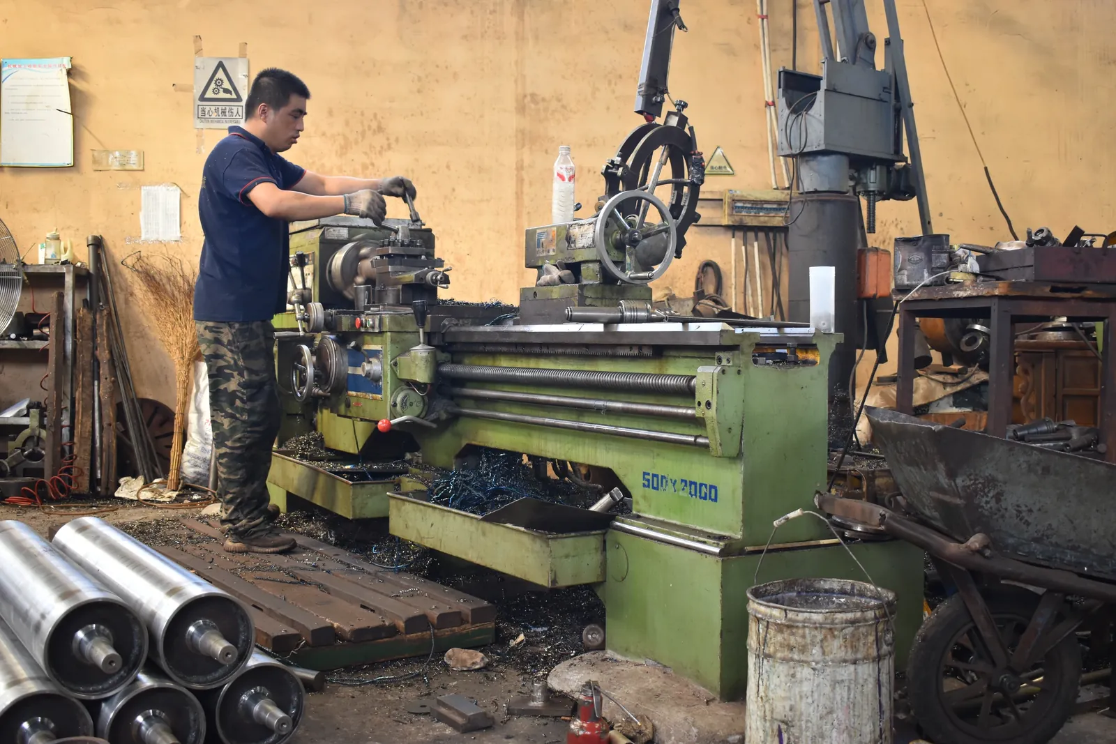 Operator adjusting equipment at a machining workstation.